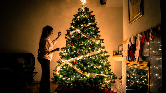Woman decorating her Christmas tree at home.