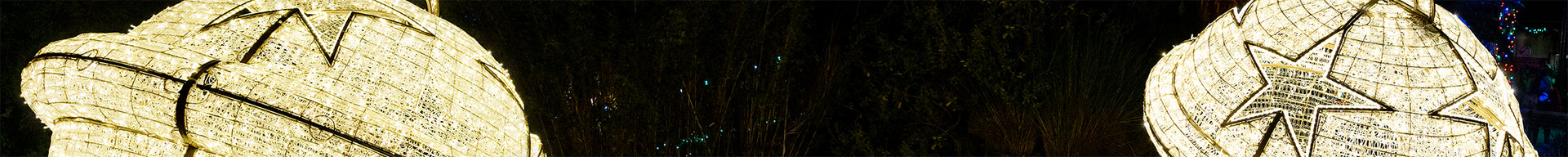 Two bell-shaped Christmas ornaments, decorated with stars and glitter, on a dark background.
