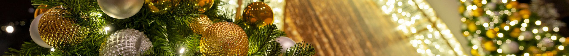A tall Christmas tree sparkling with gold and silver ornaments, bathed in warm white lights.