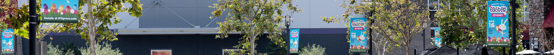 Bright blue pole banners with Easter bunnies and colorful eggs promote an upcoming event at a shopping center.