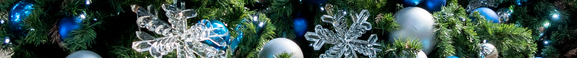 Close-up of acrylic snowflake ornaments in a Christmas tree surrounded by blue and silver ornaments.