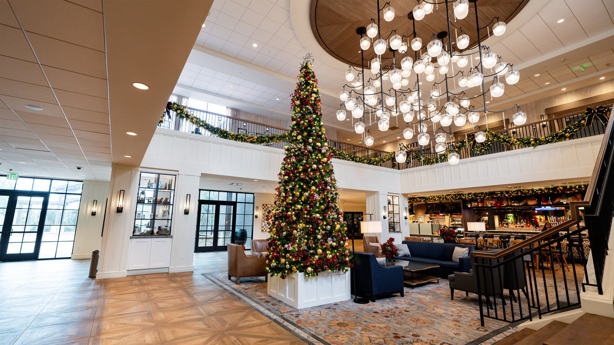 Decorative Christmas tree in a hotel lobby with festive decorations and modern furniture.