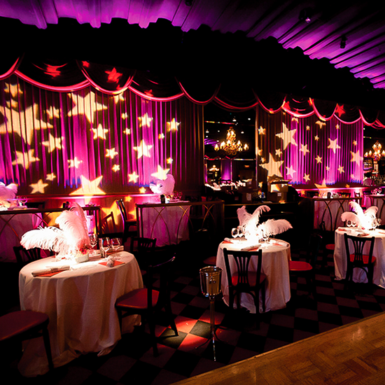 A projector displaying stars of all sizes on a purple curtain at a themed dinner party.