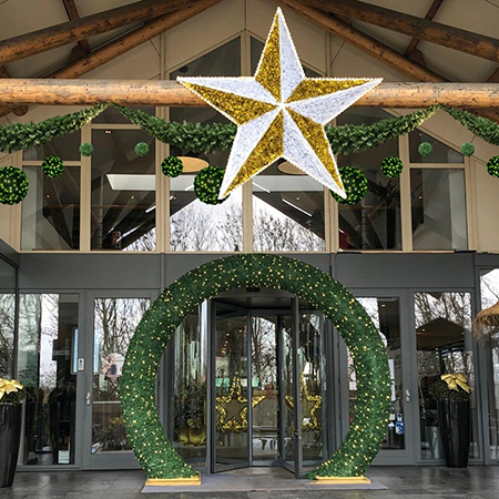 An impressive, walk-through archway in front of a building, known as the "Offenburg Arch," featuring warm mini lights and 2 gold bases.