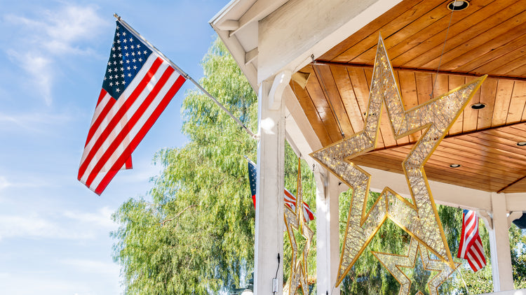 American flag and decorative star on a wooden gazebo with trees and blue sky in the background