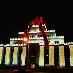 Outlet mall building covered in led net lights warm white with a giant bow on top lined with red Christmas lights