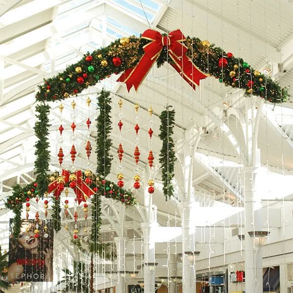 Dekra-Lite Festive tapered swag garland featuring lush greenery, sparkling ornaments, and a vibrant red bow.