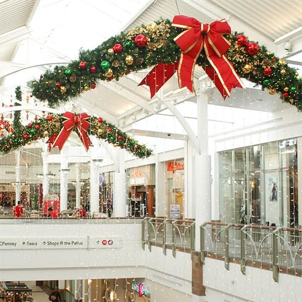 Dekra-Lite Festive tapered swag garland featuring lush greenery, sparkling ornaments, and a vibrant red bow.